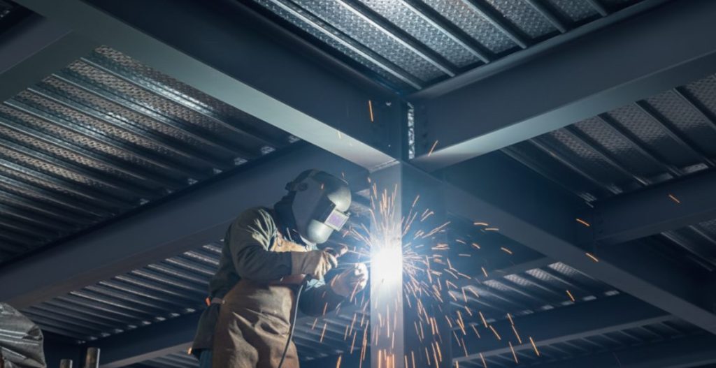 A photograph of a worker welding an H-beam.